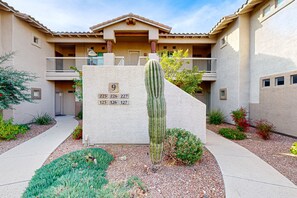 A building with a courtyard featuring a cactus, numbered signs, and a pathway.