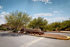 A sign for Vistoso Resort Casitas with a clear sky and trees in the background.