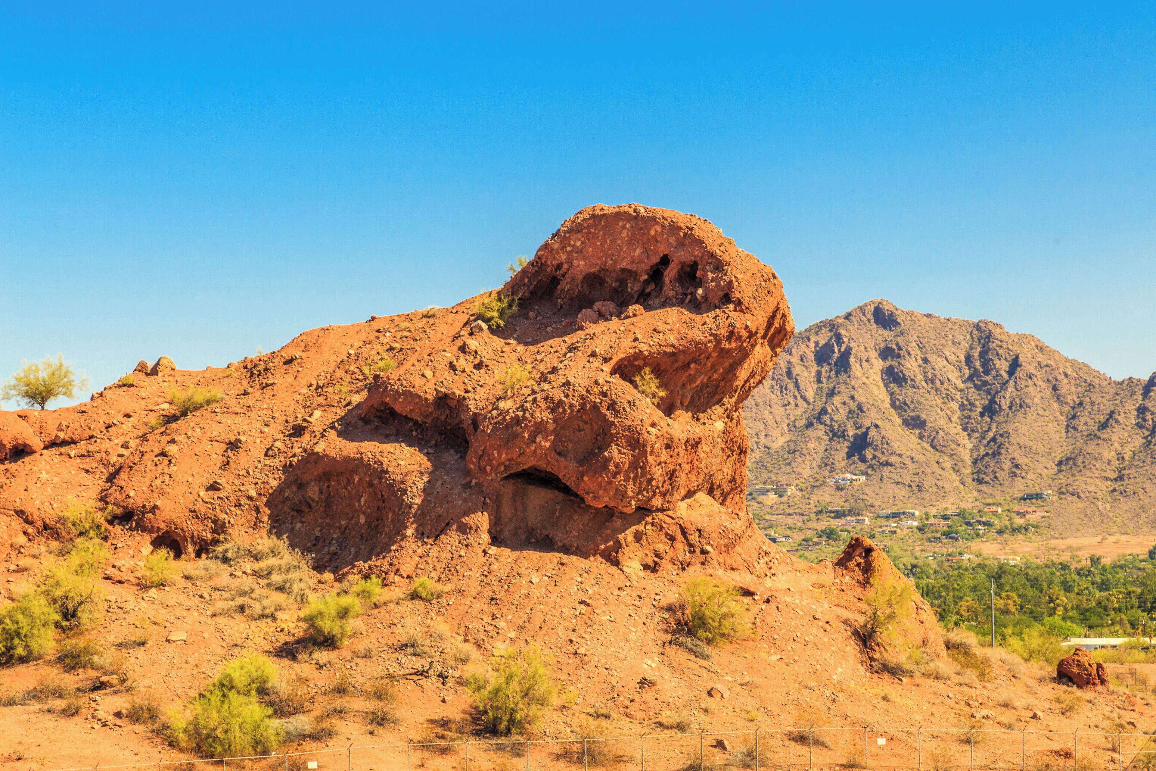 A rugged, rocky landscape with a prominent rock formation in the foreground and a mountain range in the background.