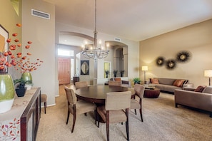A spacious living room with a round dining table surrounded by chairs, a sofa, and a coffee table. - Dog-friendly home w/outdoor pool & firepit, near the top of South Mountain (Phoenix)