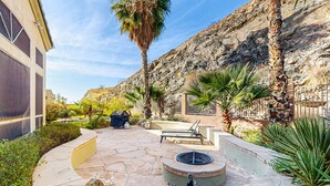 A patio area with a fire pit, seating, and a view of a rocky hillside.
