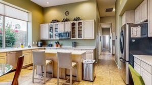 A modern kitchen with a central island, white cabinetry, and stainless steel appliances.