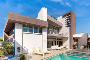 A modern two-story house with a swimming pool, outdoor seating, and a balcony. - Stunning luxury home w/pool, spa, outdoor fireplace & mountain views (Palm Springs)