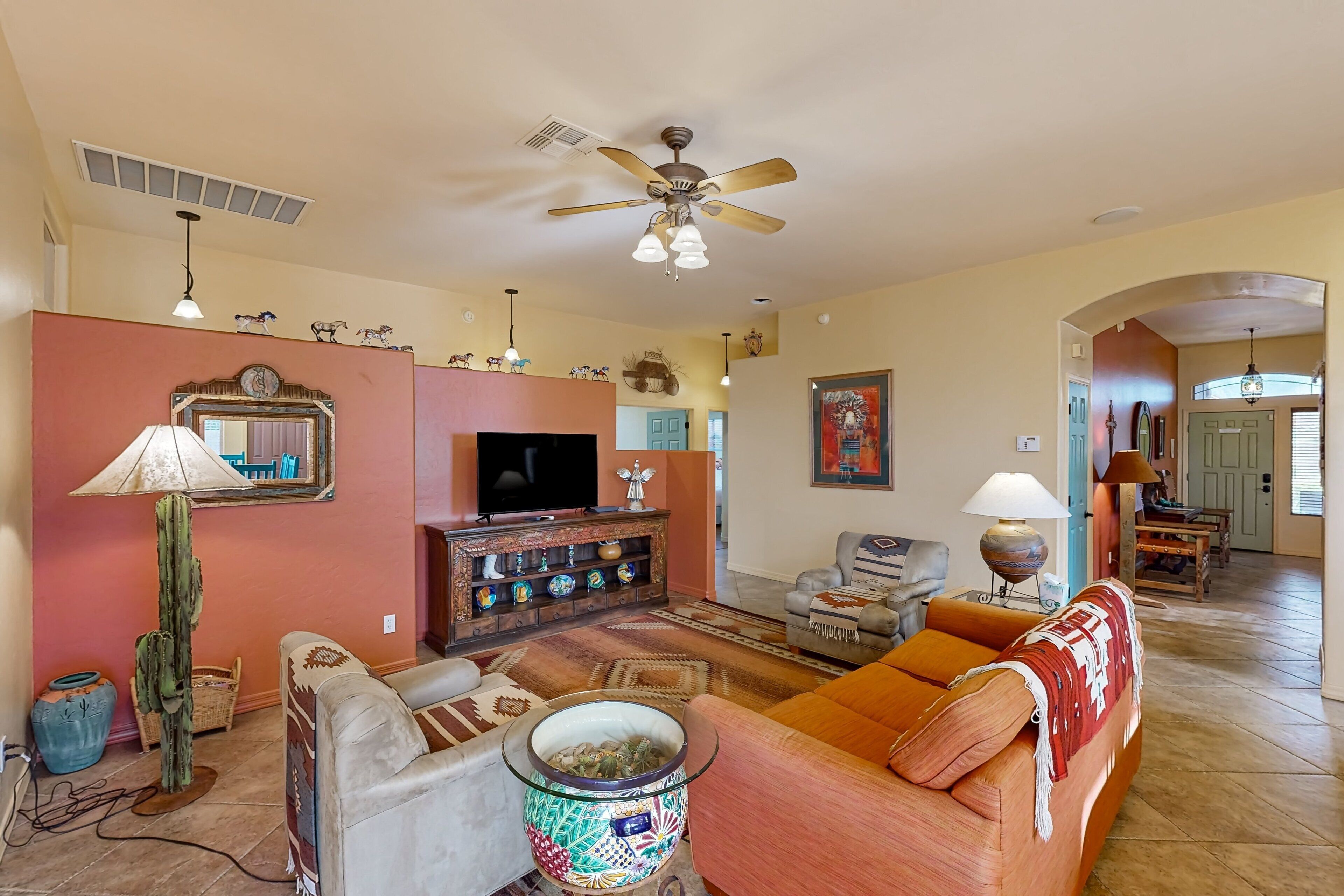 A living room with a ceiling fan, a television, and a sofa.