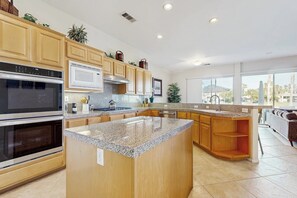 A modern kitchen with granite countertops, stainless steel appliances, and wooden cabinetry. - PGA West course-side house with shared pool, hot tub, and golf access (La Quinta)