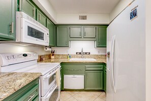 A compact kitchen with green cabinets, a white microwave, stove, and refrigerator. - Ground-floor condo with private hot tub, 8 on-site pools, & tennis/pickleball (Palm Springs)