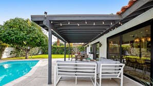 Uma área de estar coberta ao ar livre com piscina, mesa e cadeiras.
