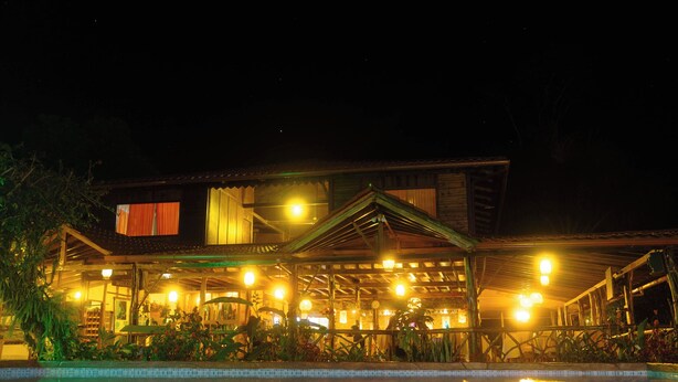 A nighttime view of a building with a pool reflecting lights. - Superior Room 1 or 2 beds Suchipakari Jungle Lodge (Napo)