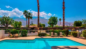 A swimming pool with palm trees, a fenced area, and a mountain view. - Modern palm-surrounded condo with mtn views, heated pool, & AC - dog-friendly (Palm Springs)