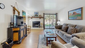 Una sala de estar con chimenea, sofá, mesa de centro y televisor sobre un mueble.
