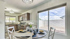 A modern kitchen with a dining area, large windows, and a view of a brick wall. - Single-level dog-friendly home with private pool, grill, enclosed backyard, & AC (Chandler)
