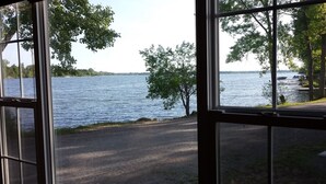 Näkymä ikkunasta, jossa näkyy järvi, puita ja päällystetty kävelyreitti.