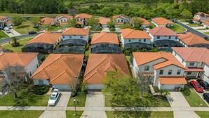 A residential area with houses featuring red-tiled roofs and solar panels. - Gorgeous Executive Disney Pool Home in High Grove Clermont 4BR/ 3BA (Clermont)