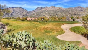 Un terrain de golf avec un cactus au premier plan, un paysage désertique et des montagnes en arrière-plan.