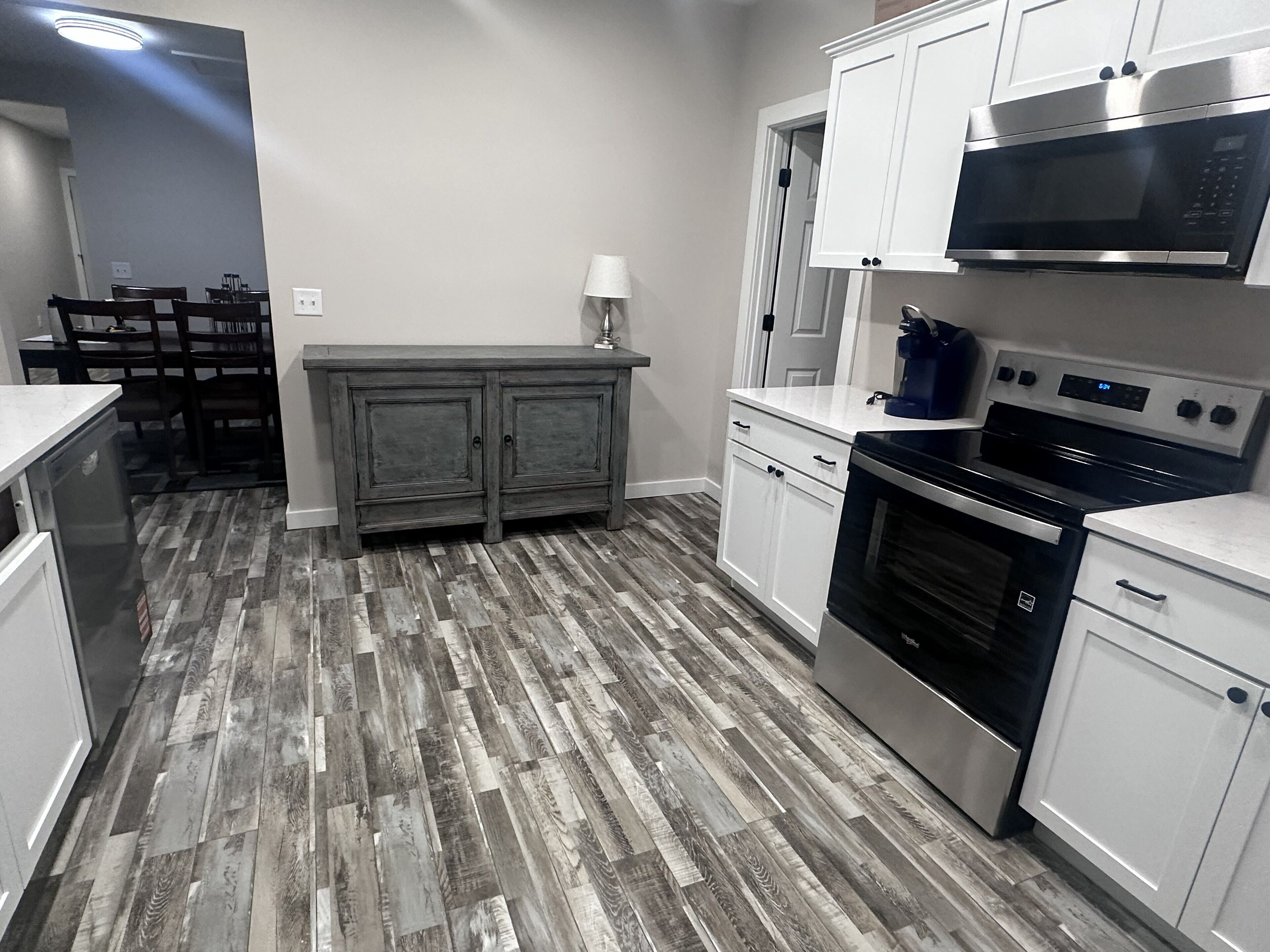 A modern kitchen with white cabinets, a stainless steel stove, and a microwave.