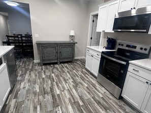 A modern kitchen with white cabinets, a stainless steel stove, and a microwave. - State Street Retreat (Big Rapids)