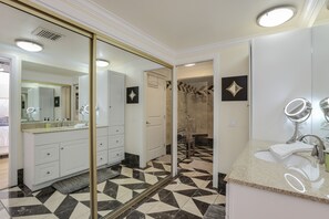 Une salle de bain moderne avec un grand miroir, un lavabo avec un meuble-vasque et un espace douche.