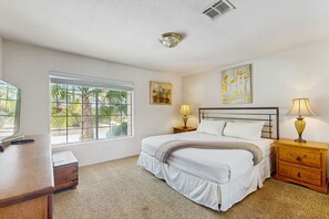 A bedroom with a bed, bedside tables, a desk, a window with blinds, and artwork on the wall. - Luxurious home with an outdoor kitchen, private pool & spa - close to golf (Bermuda Dunes)