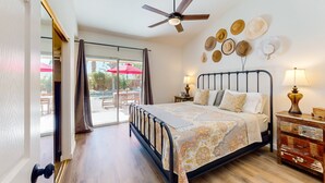 A bedroom with a bed, bedside lamps, a ceiling fan, a wall-mounted hat display, and a sliding glass door to an outdoor area. - Dog-Friendly Home w/ a Private Pool, Pool Spa, Firepit, & Patio - 3BR - #66716 (La Quinta)