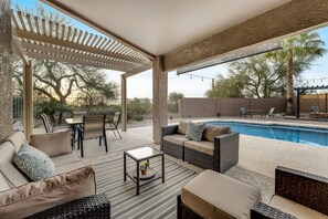 Un espace extérieur aménagé en terrasse, avec une piscine, des meubles en osier et une pergola.