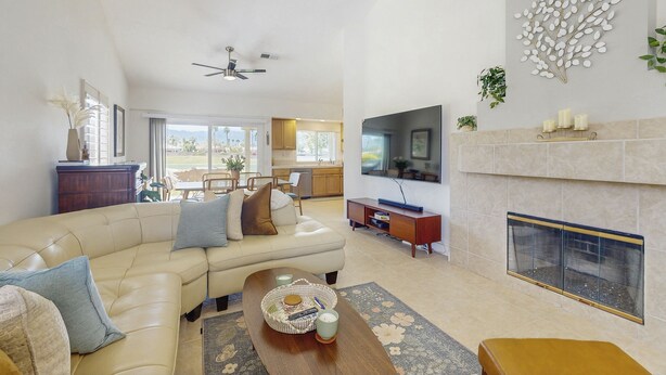 A spacious living room with a beige sofa, a coffee table, and a fireplace. - Sun, Comfort, and Stunning Views, Shared pool & Dog-friendly (Palm Desert)