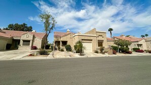 A residential street with houses featuring red-tiled roofs and stucco exteriors. - Sun, Comfort, and Stunning Views, Shared pool & Dog-friendly (Palm Desert)
