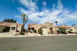 A residential street with houses featuring red-tiled roofs and stucco exteriors. - Sun, Comfort, and Stunning Views, Shared pool & Dog-friendly (Palm Desert)