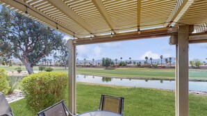 A covered patio with a view of a golf course and a pond. - Sun, Comfort, and Stunning Views, Shared pool & Dog-friendly (Palm Desert)