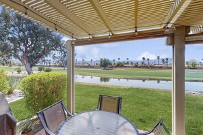 A covered patio with a view of a golf course and a pond. - Sun, Comfort, and Stunning Views, Shared pool & Dog-friendly (Palm Desert)