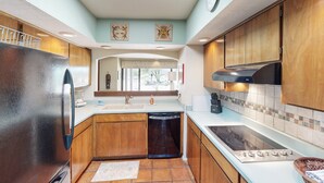 Une cuisine moderne avec des meubles en bois, un réfrigérateur en acier inoxydable, un lave-vaisselle et un four encastré.