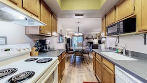 A kitchen with wooden cabinets, a white stove, a microwave, and a sink. - Stylish ground floor condo - patio, pool, fireplace, full kitchen & washer/dryer (Sedona)