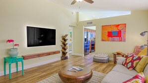 Un soggiorno moderno con una TV a schermo piatto, un tavolino in legno, un divano e un quadro astratto dai colori vivaci.