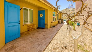 Un edificio giallo con porte e finestre blu, un piccolo portico e un albero con lanterne appese.