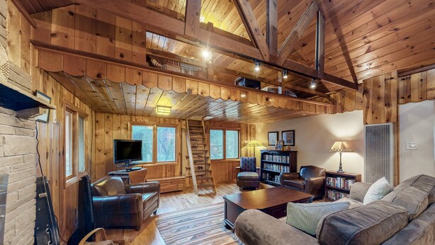 Ein gemütliches Holzhaus-Interieur mit Kamin, Ledermöbeln und einem Fernseher.