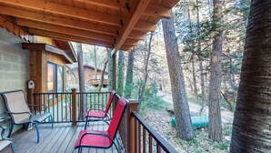 Eine Holzdielen-Terrasse mit Stühlen und einem Tisch, mit Blick auf eine bewaldete Landschaft.