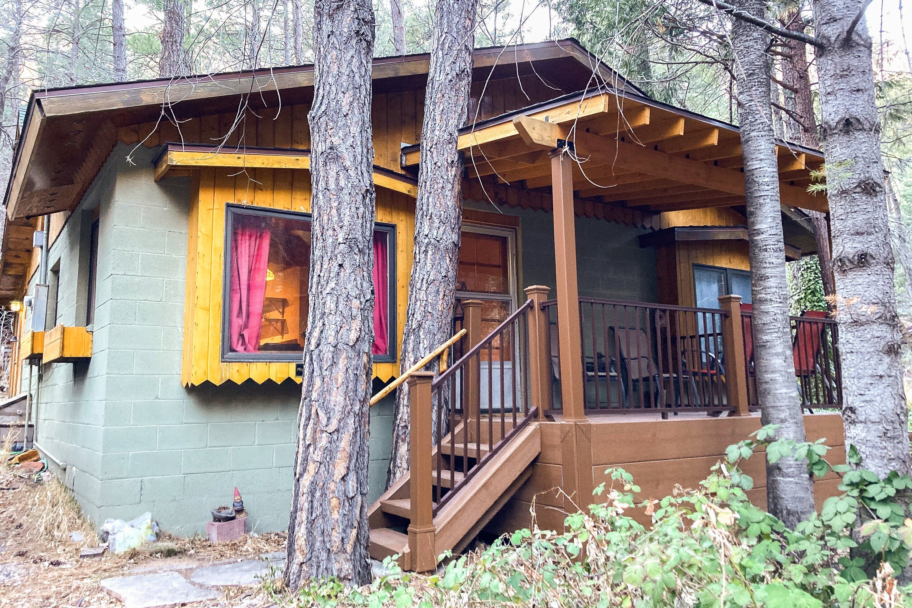 Une cabane avec une façade en bois, une véranda et un escalier menant à l’entrée.