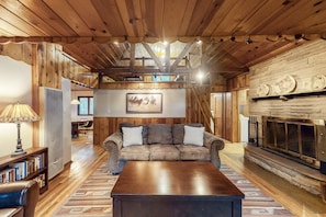 Una sala de estar acogedora con techo de madera, chimenea, sofá y una mesa de centro.