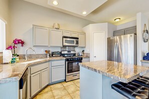 A modern kitchen with white cabinets, a stainless steel refrigerator, a built-in oven, and a granite countertop. - Stunning home  with private heated pool, spa, firepit, grill & alfresco dining (Cathedral City)