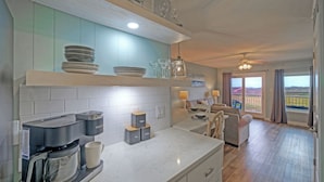 A modern kitchen with a marble countertop, built-in appliances, and a dining area with a view. - Rest Ashored by Avantstay Port A Condo + Beach Access + Pickleball Court + Basketball Court (Port Aransas)