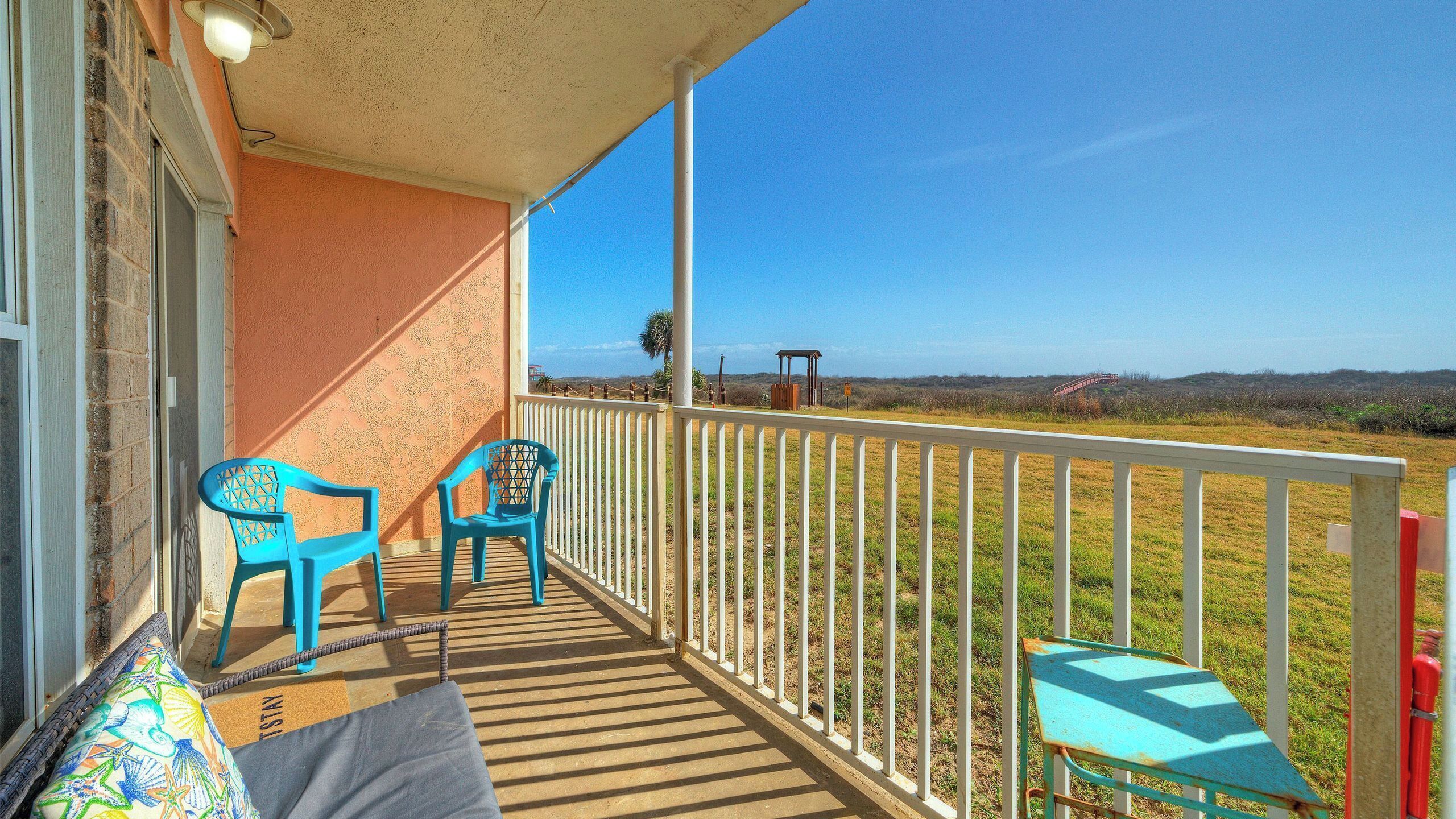 Ein Balkon mit Blick auf die Landschaft, ein Holzboden und zwei blaue Stühle.