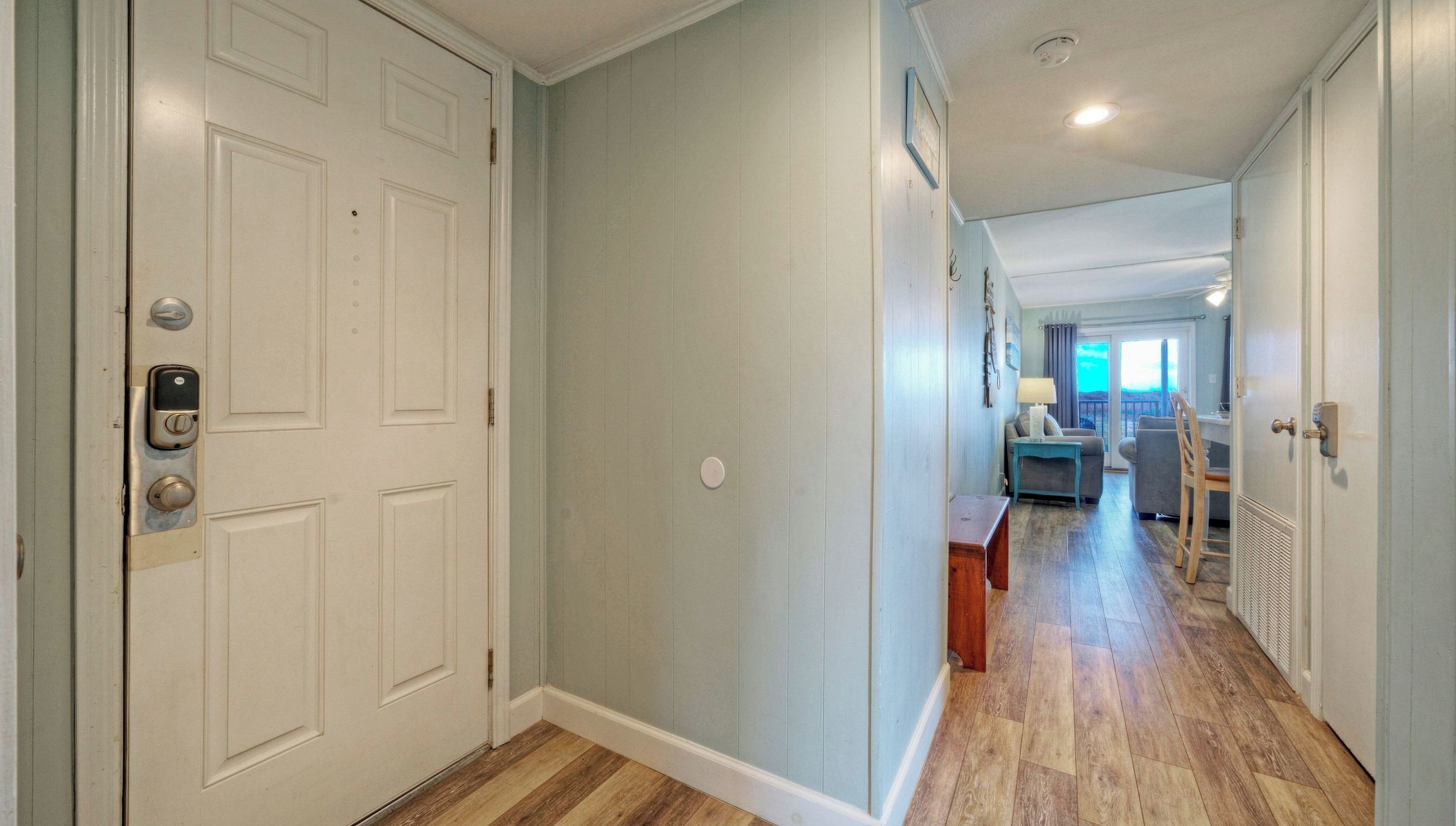 A hallway with a door, a small table, and a chair.