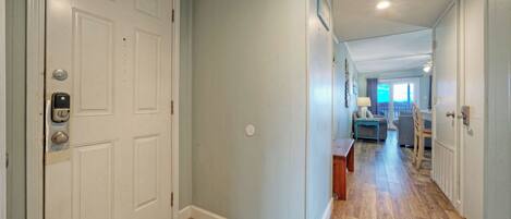 A hallway with a door, a small table, and a chair.