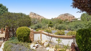 A landscaped garden with a stone wall, a small pond, and rocky hills in the background. - Red Rock-view oasis with beautiful veranda, central AC, W/D (Sedona)