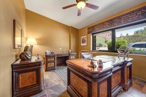 A spacious room with a large wooden desk, a ceiling fan, and a window with a view of a mountain. - Red Rock-view oasis with beautiful veranda, central AC, W/D (Sedona)