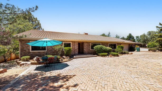 A single-story house with a brick exterior, a tiled roof, and a paved driveway. - Red Rock-view oasis with beautiful veranda, central AC, W/D (Sedona)