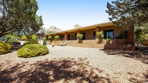 A two-story building with a covered patio area, surrounded by landscaped gardens and trees. - Red Rock-view oasis with beautiful veranda, central AC, W/D (Sedona)