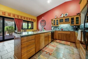 A kitchen with wooden cabinets, a marble countertop, and a red wall. - Red Rock-view oasis with beautiful veranda, central AC, W/D (Sedona)
