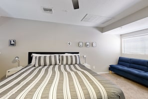 A bedroom with a large bed, a blue sofa, and a ceiling light. - Inviting desert oasis with modern decor, pool, and hot tub (Scottsdale)