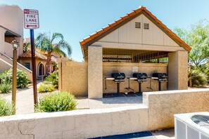 A fire lane with a no parking sign, a covered barbecue area with grills, and a building with a tiled roof. - Inviting desert oasis with modern decor, pool, and hot tub (Scottsdale)