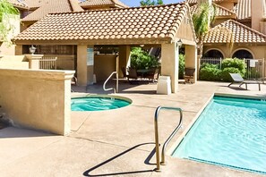 A pool area with a hot tub, lounge chairs, and a covered seating area. - Inviting desert oasis with modern decor, pool, and hot tub (Scottsdale)